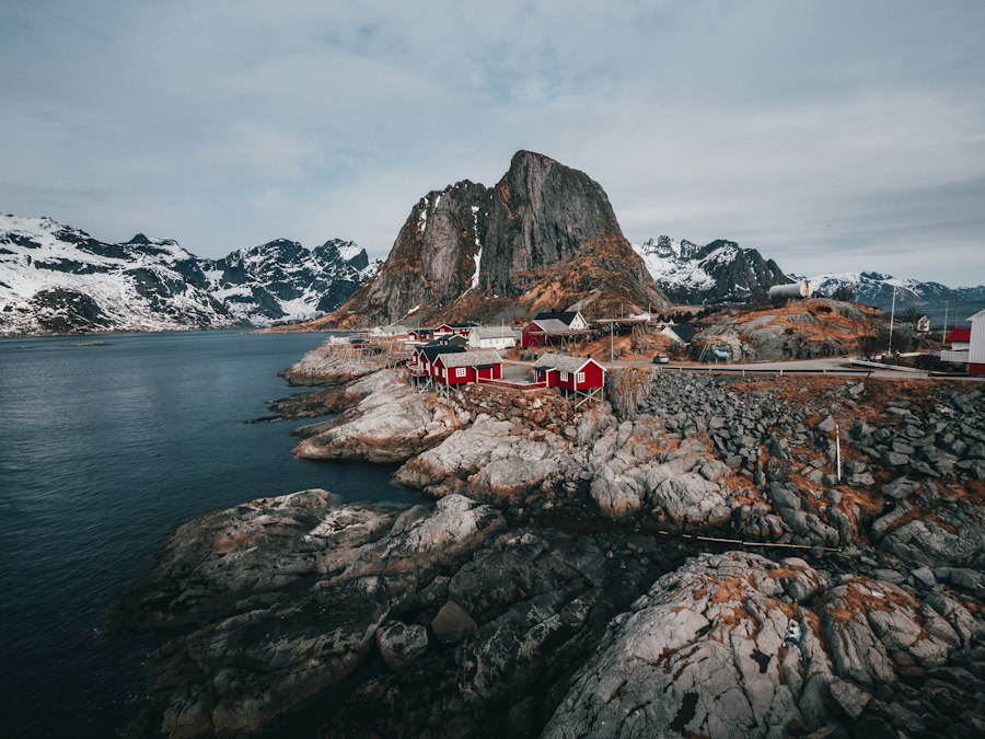 Red fishermen cabins on a rocky shore beneath snow-covered peaks in Lofoten, Norway