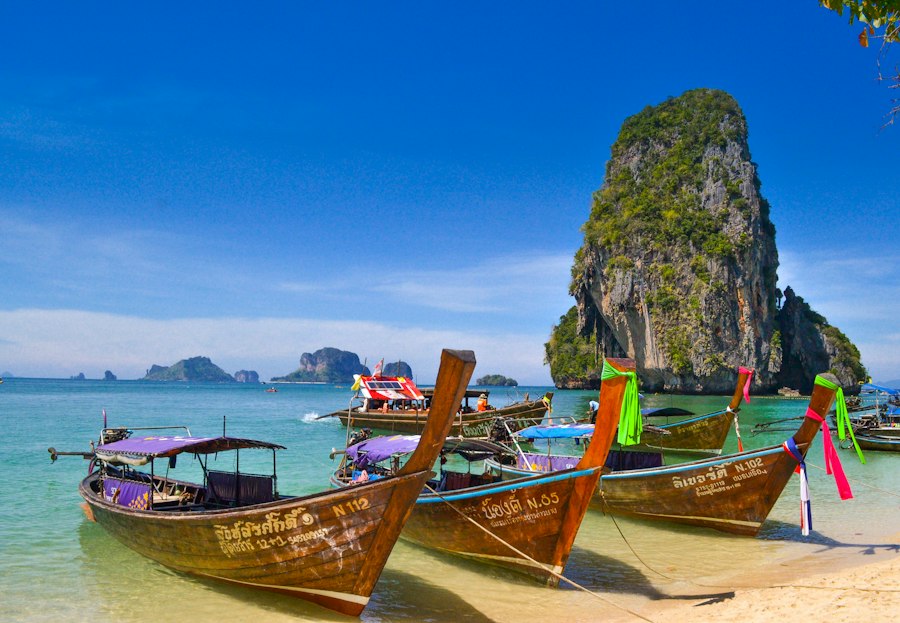 Traditional longtail boats moored on Railay Beach beneath limestone cliffs in Thailand