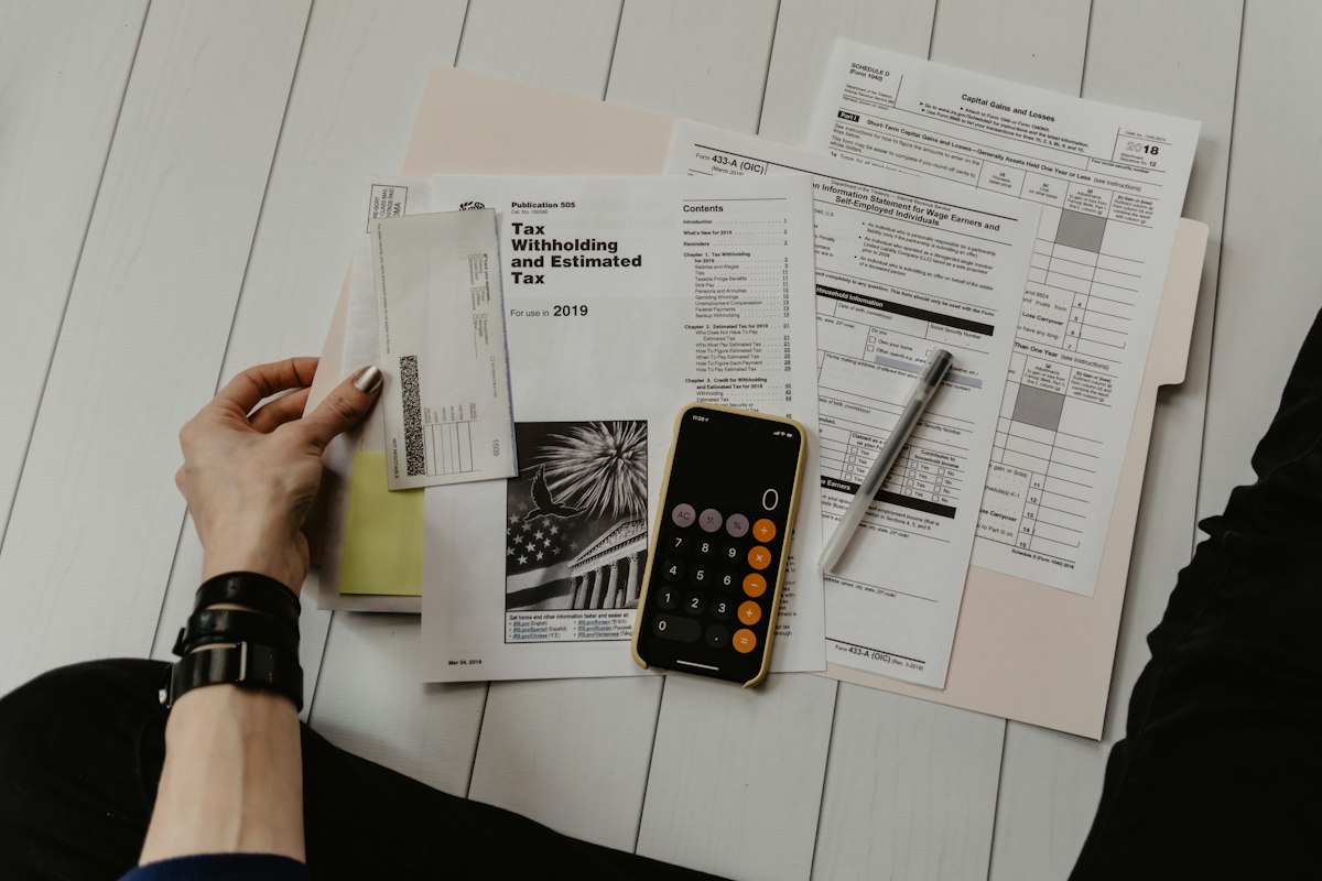 Person reviewing tax forms and paper receipts with a calculator on a clean white table