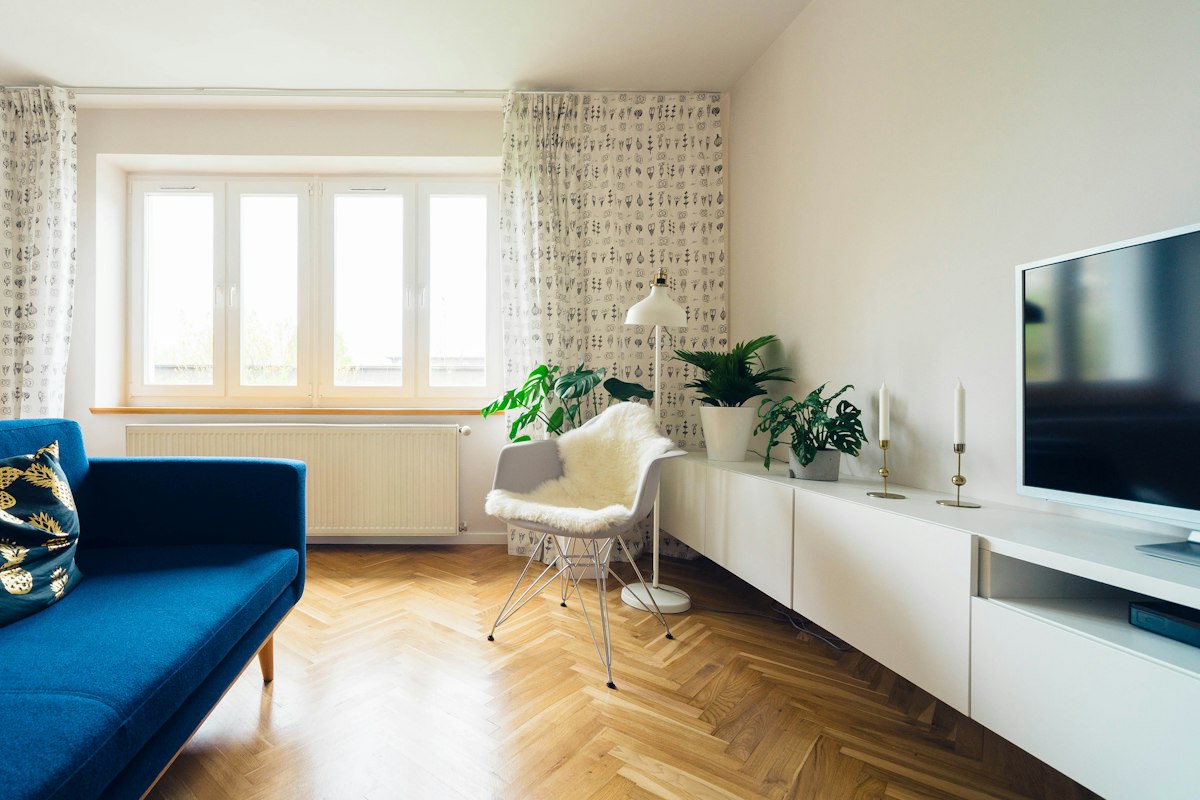 Bright living room with a blue sofa, white sideboard and tall windows