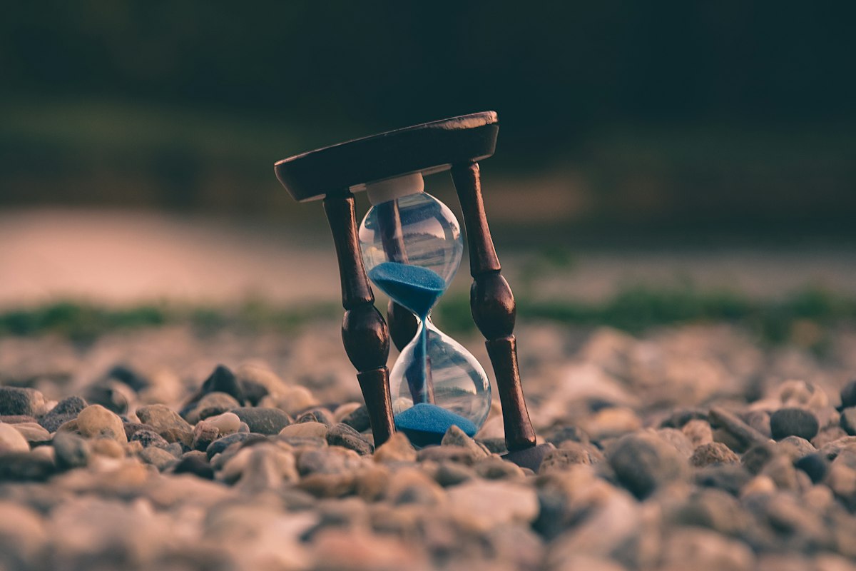 An hourglass standing on smooth pebbles at dusk