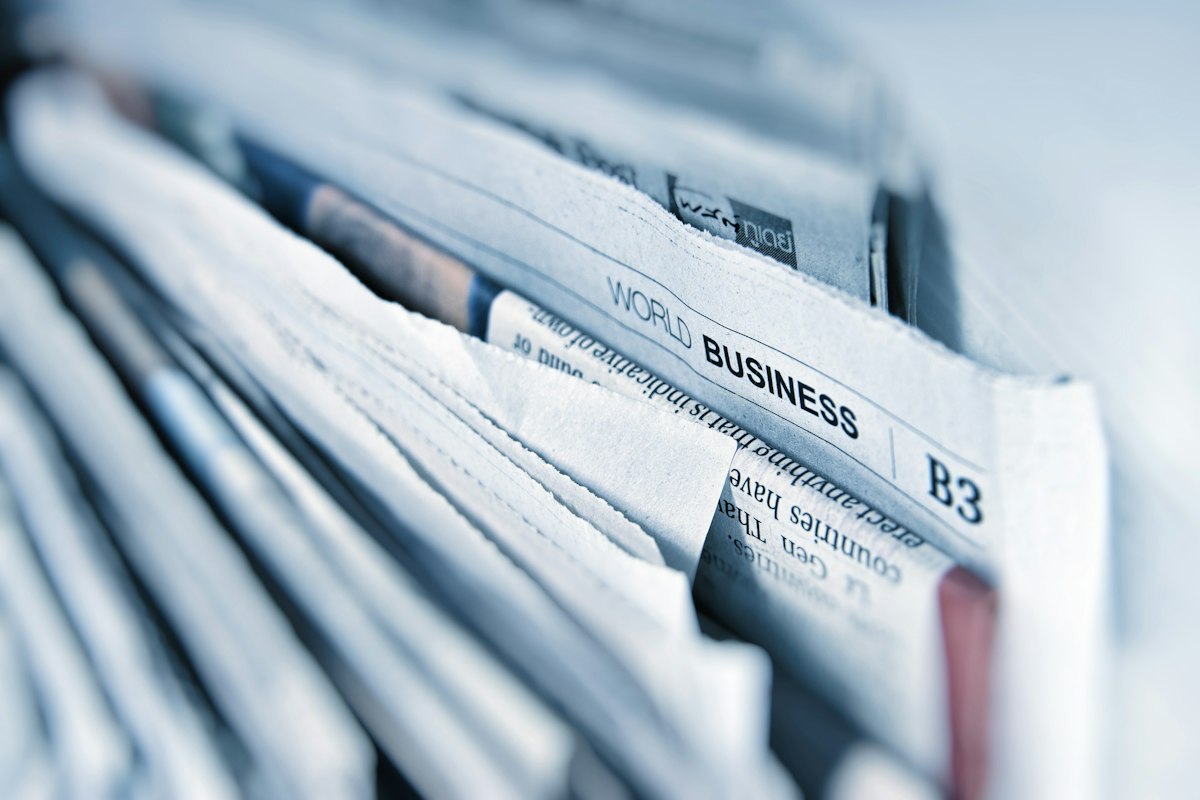 A stack of folded newspapers with the business section on top