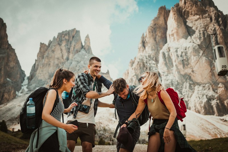 Group of friends hiking together below dramatic mountain peaks