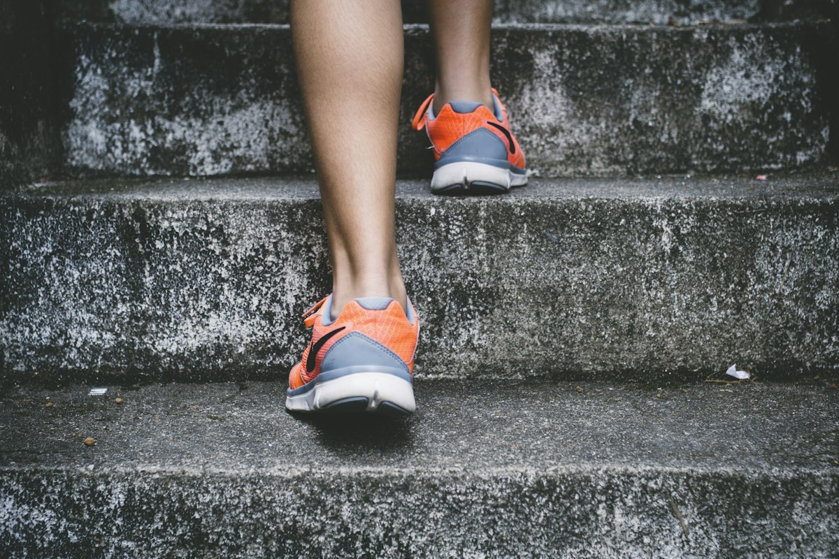 A runner in orange trainers climbing a flight of concrete steps