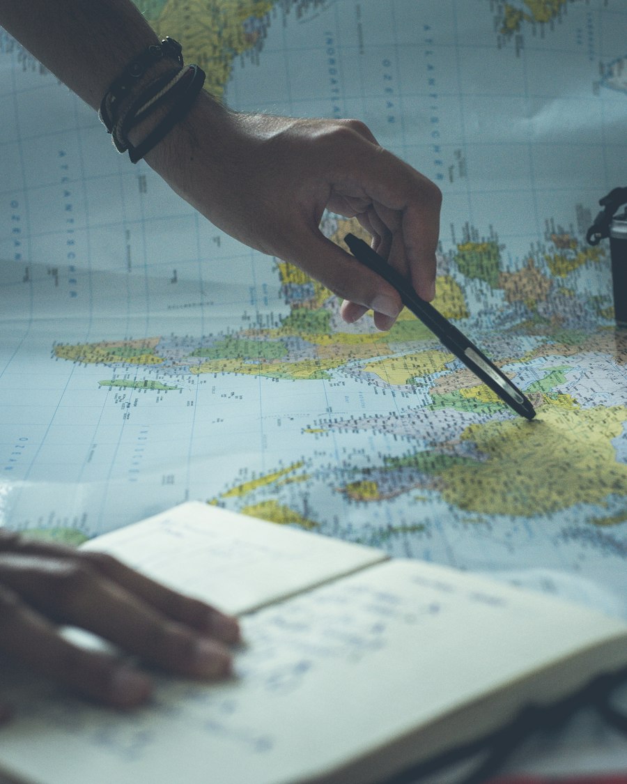 A travel specialist tracing a January route across a paper map beside a handwritten itinerary notebook